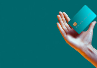 a light skinned hand holding a credit card on a turquoise background