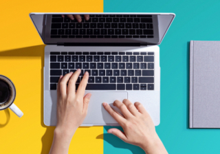 blue and yellow background with a person's hands over a laptop