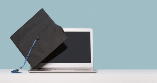A black graduation cap on the corner of a laptop with a blue background