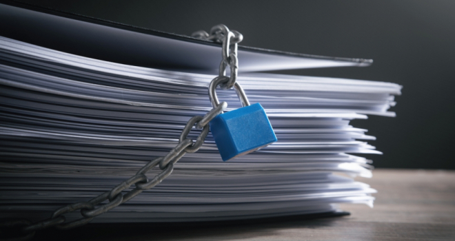 pile of paper documents with a chain and padlock around