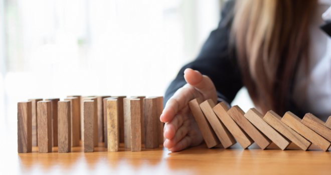 Personal guarantee insurance sees 'steep rise' as SMEs guard against failure hand stopping chain reaction of wooden blocks falling over